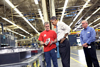 President Barack Obama examines a part held by Mike Clements during a tour of Allison Transmission in Indianapolis, Ind. 