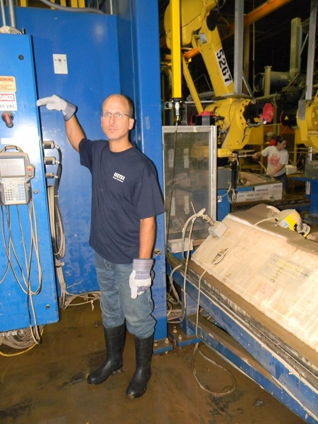 An Autoneum employee points to where the floodwater rose nearly above his head