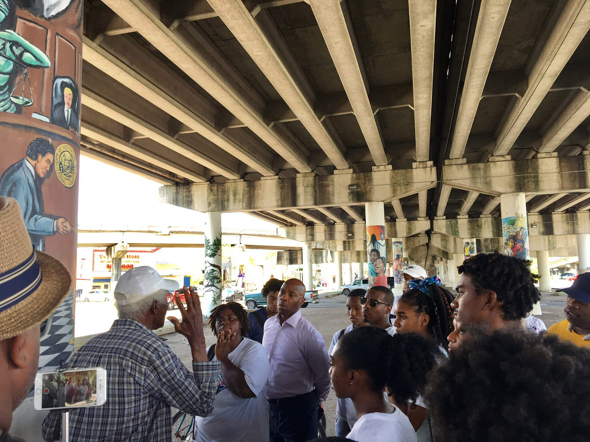 A community meeting under the overpass where residents listen to another person speak