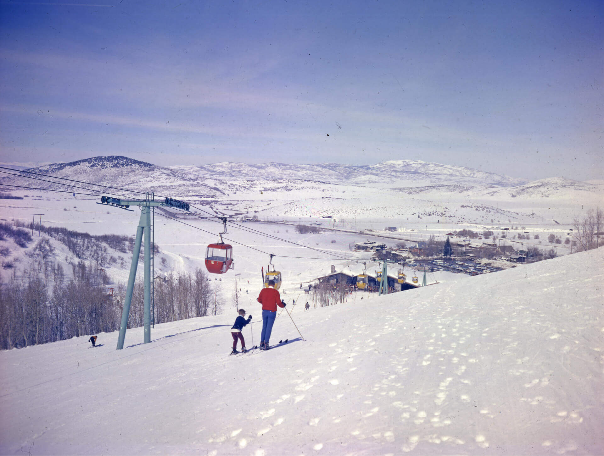 A father and son skiing next to the ski gondola