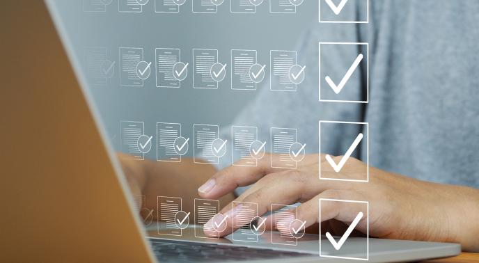 Person typing on a laptop with superimposed check marks in front of them