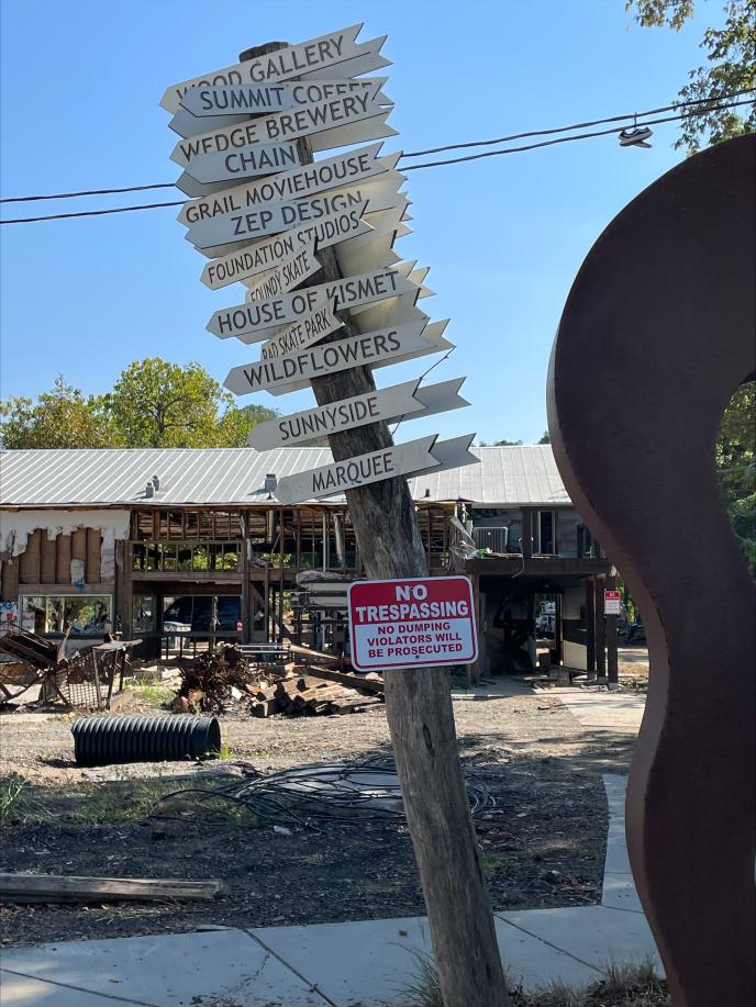 Photo of a directional sign with major damage in the background