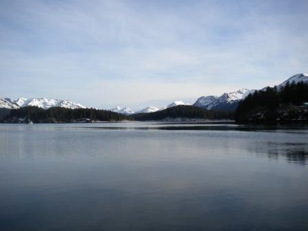 A photograph of a lake with white cap mountains in the background.
